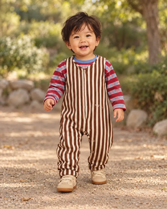 Toddler in a brown and cream striped Mumzers Onezer walking on a garden path