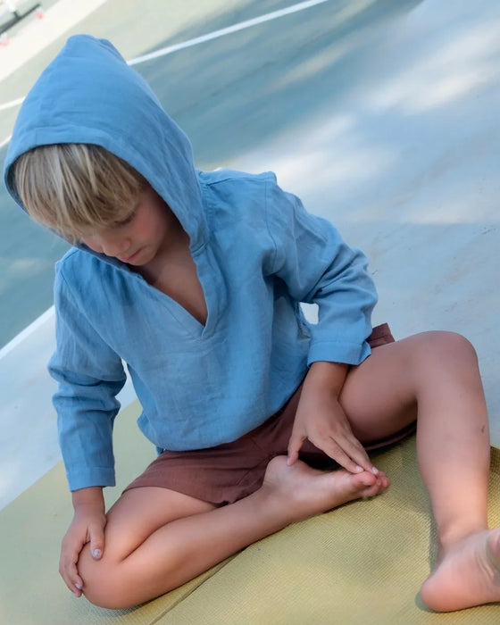 Kid in a blue Breezer, hood up, sitting on the court